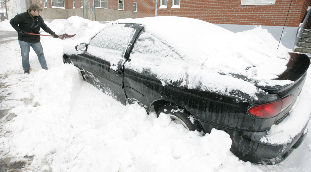 Noel Chenier/Telegraph-Journal Bjorn Lisik diggs out his car on Carmarthen Street in Uptown Saint John on Friday morning after it was buried overnight by a winter storm and city plow crews.
